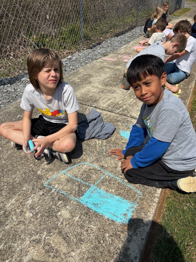 two male students sitting on the sidewalk with sidewalk chalk
