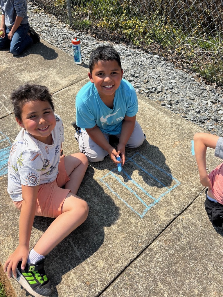 two male students sitting on the sidewalk with sidewalk chalk
