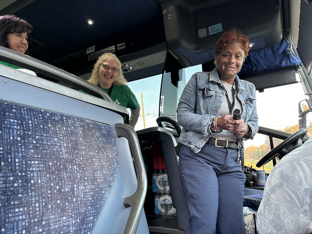 Bus driver and 2 teachers standing in the front of the bus