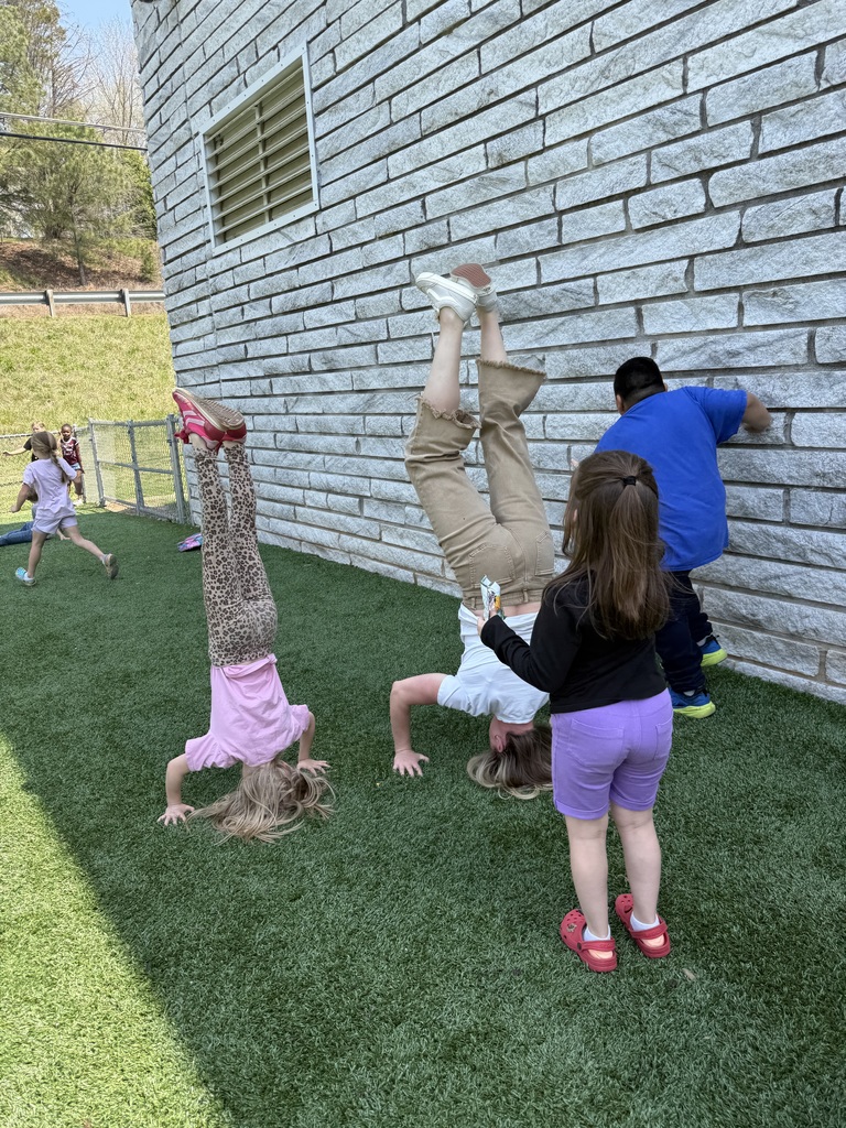Two people on  a playground doing a hand stand