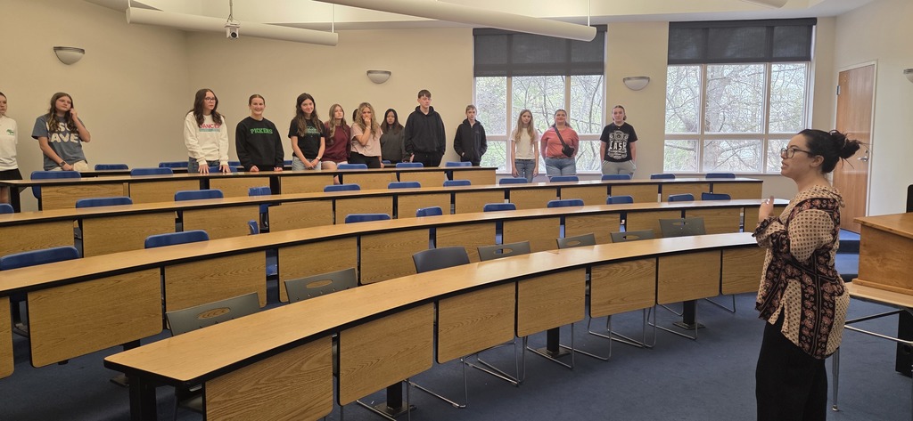 Students standing in the back of a lecture hall style classroom