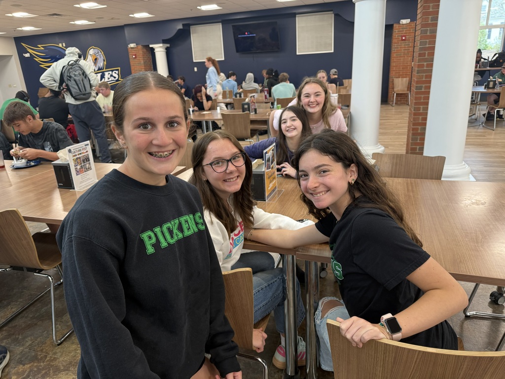 5 girls gathered around a table in the Reinhardt cafeteria, smiling at the camera