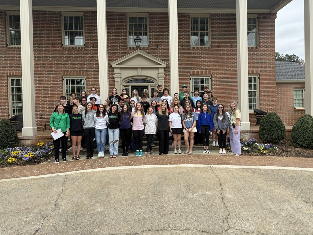 Group of students and teachers standing in front of a columned building
