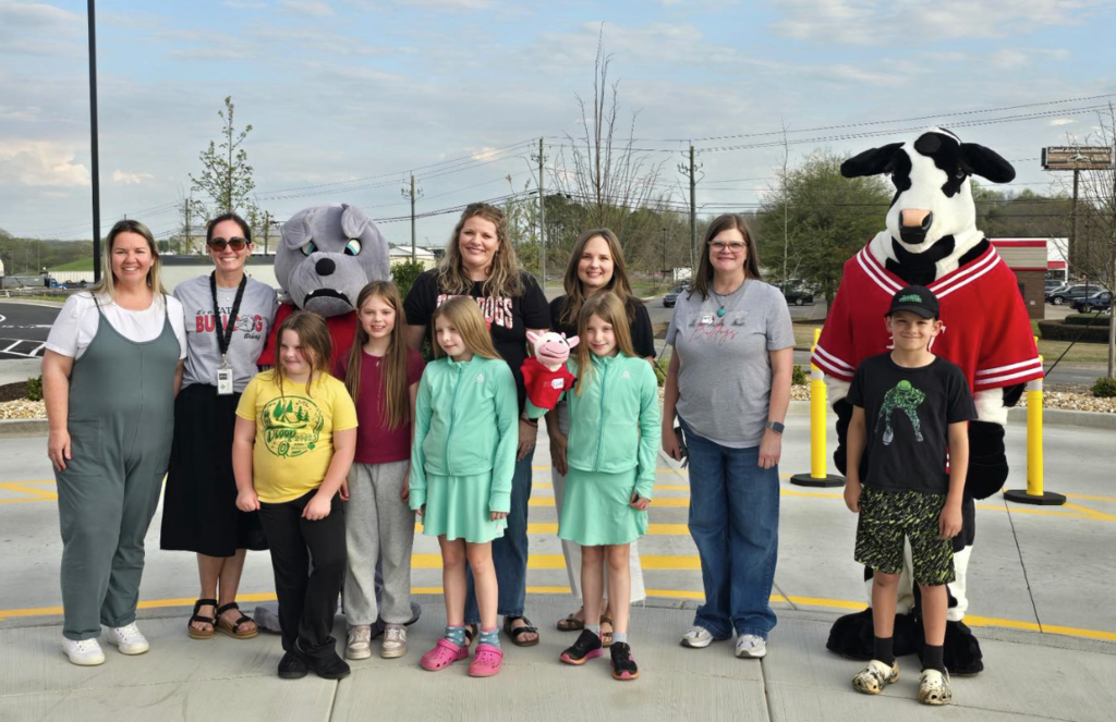 Group of people standing with a cow and bulldog costume