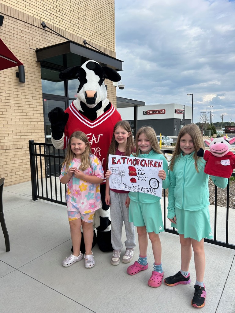 four female kids standing with a cow costume at a chick fil a building