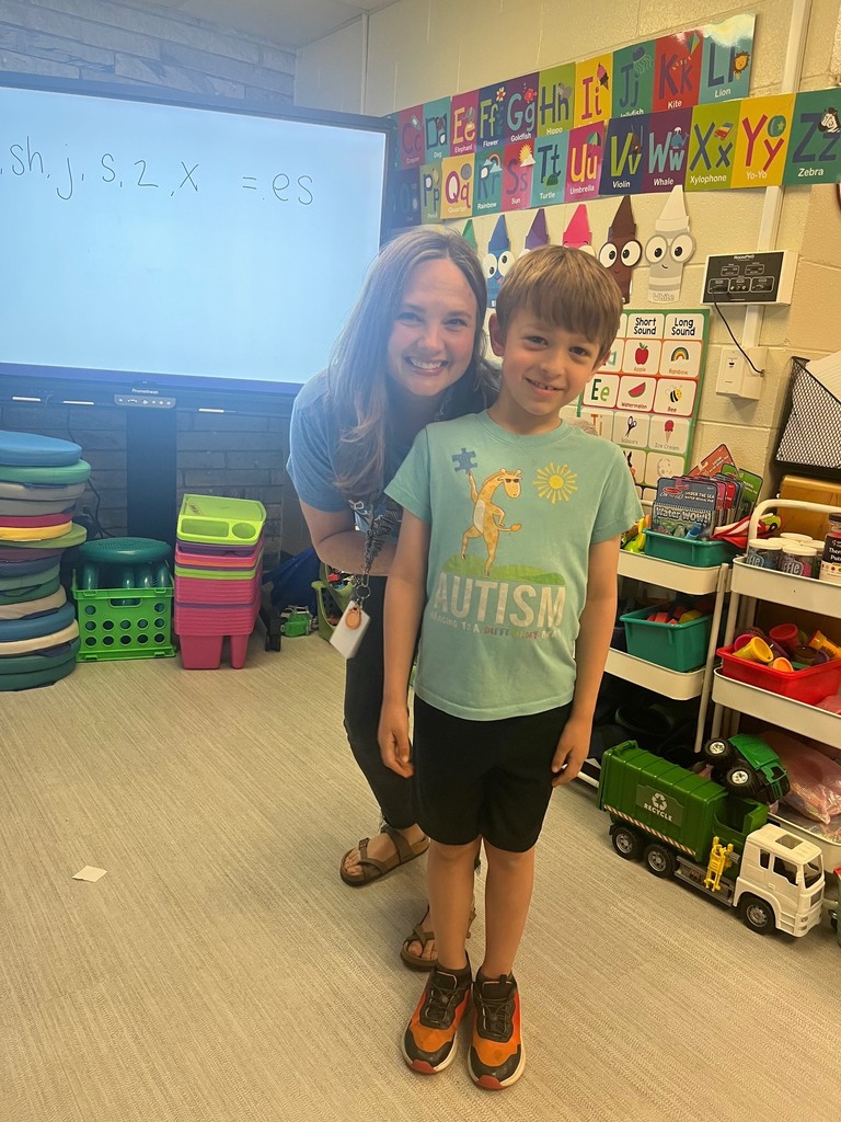teacher and student wearing blue standing in a classroom