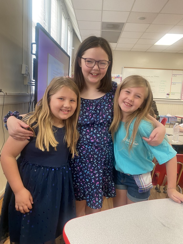 three students in a classroom wearing blue