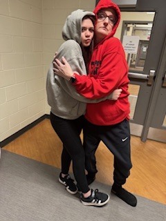 Teacher and student wearing hoodies hugging