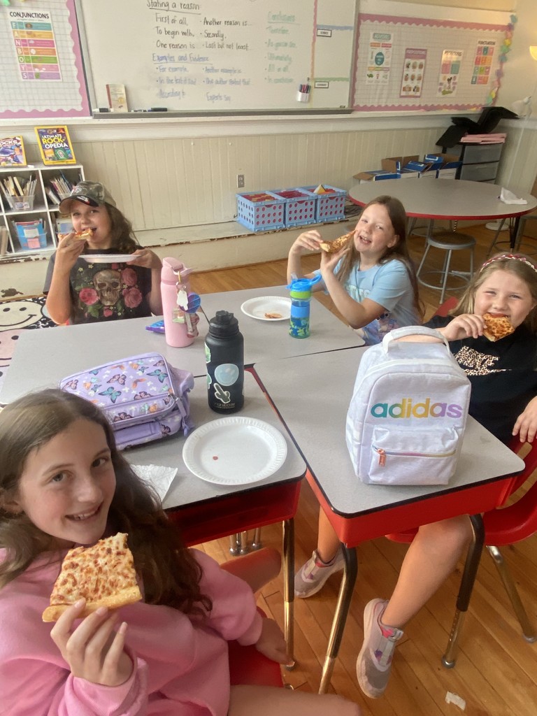 four girls sitting at a table eating pizza
