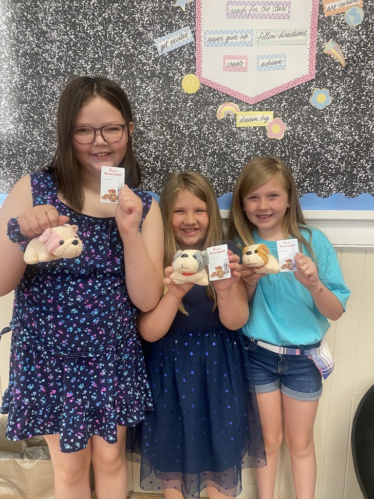 Three girls standing together holding chick fil a gift cards and small bulldog stuffed animals