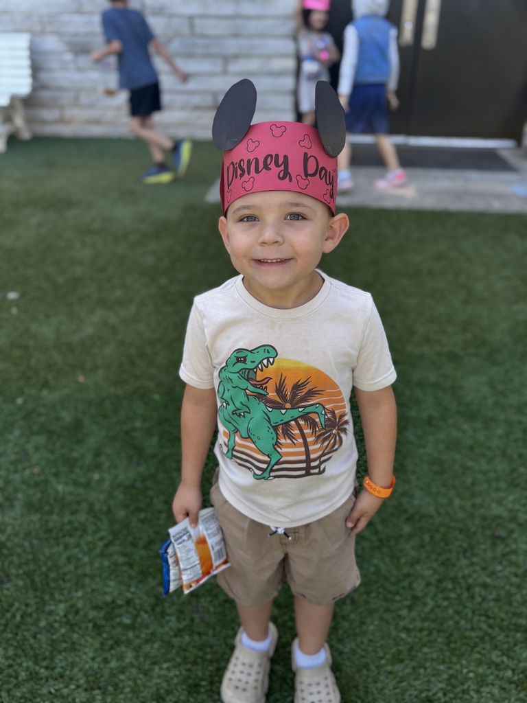 Boy on playground wearing a red hat that says Disney Day