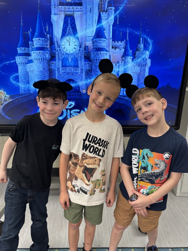 Three kids wearing mickey  mouse ears. They are standing in front of Cinderella's castle projected on a screen.