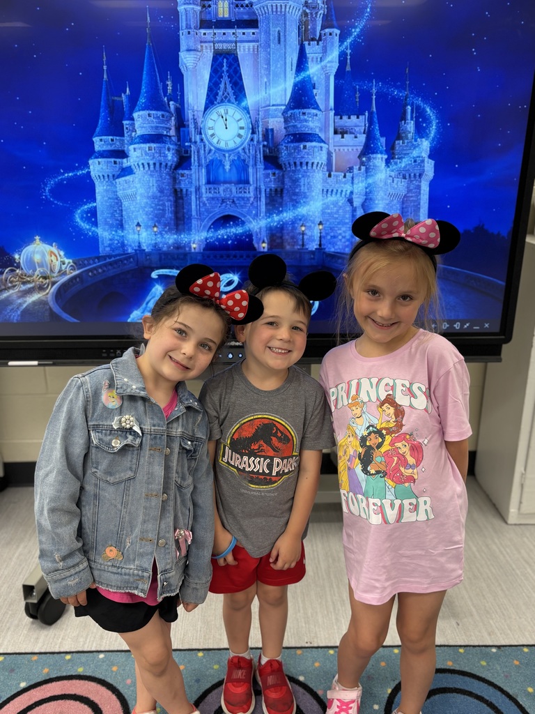 Three kids wearing mickey and minnie mouse ears. They are standing in front of Cinderella's castle projected on a screen.
