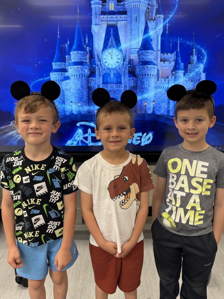 Three kids wearing mickey mouse ears. They are standing in front of Cinderella's castle projected on a screen.
