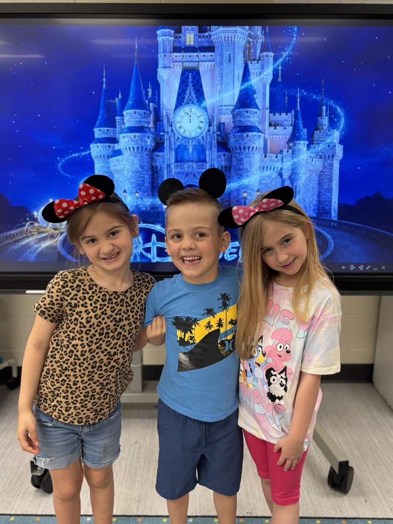 Three kids wearing mickey and minnie mouse ears. They are standing in front of Cinderella's castle projected on a screen.