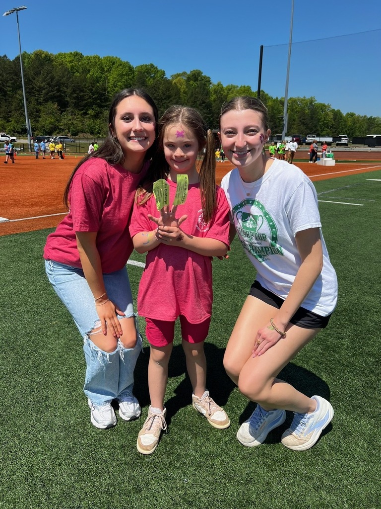 Two highschool age girls and one small female child. The smaller girl is holding stickers