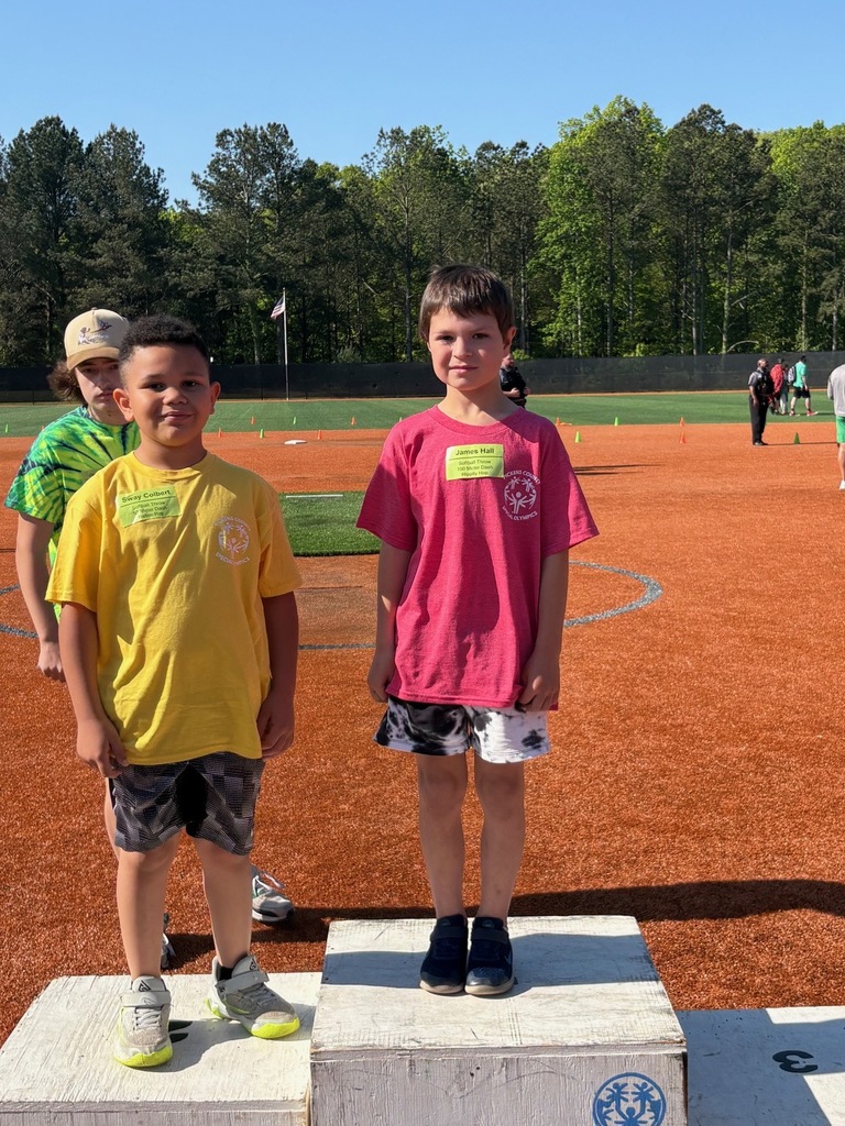 Two kids standing on a podium. One in yellow, one in pink