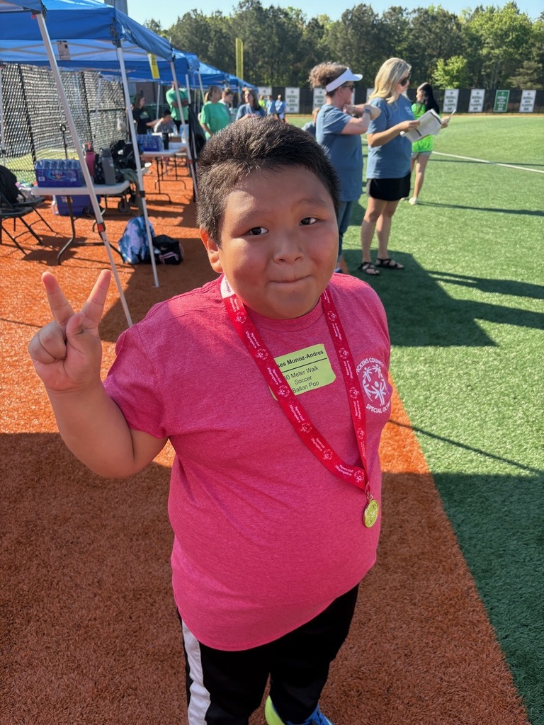 Boy holding up two fingers, wearing a pink shirt