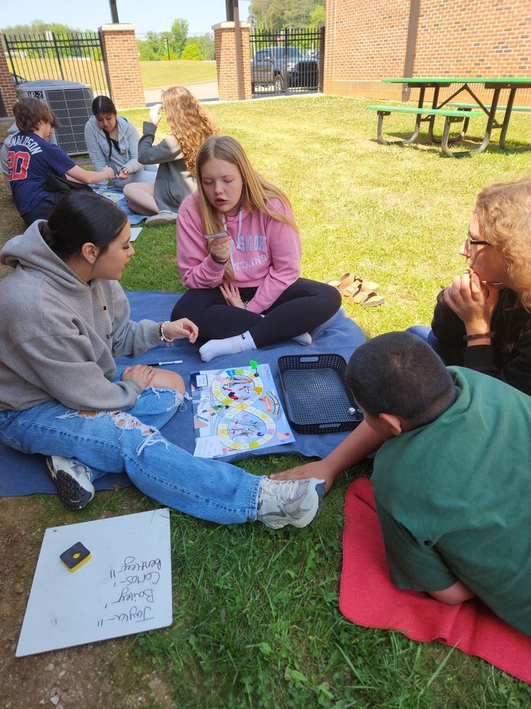 Group of students sitting on a blanket working on an activity