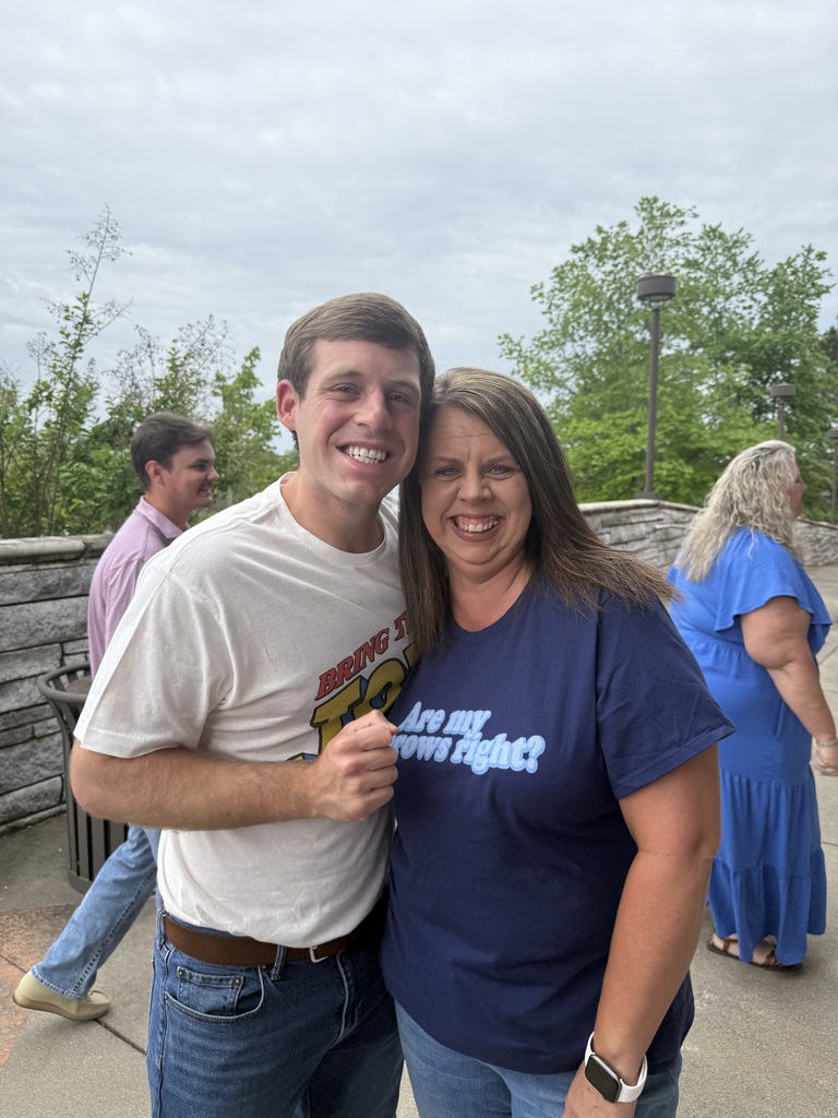 woman and a man standing outside close together with their arms around each other. 