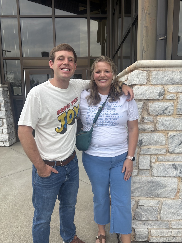 woman and a man standing outside close together with their arms around each other. 