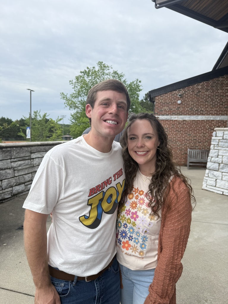 woman and a man standing outside close together with their arms around each other. 