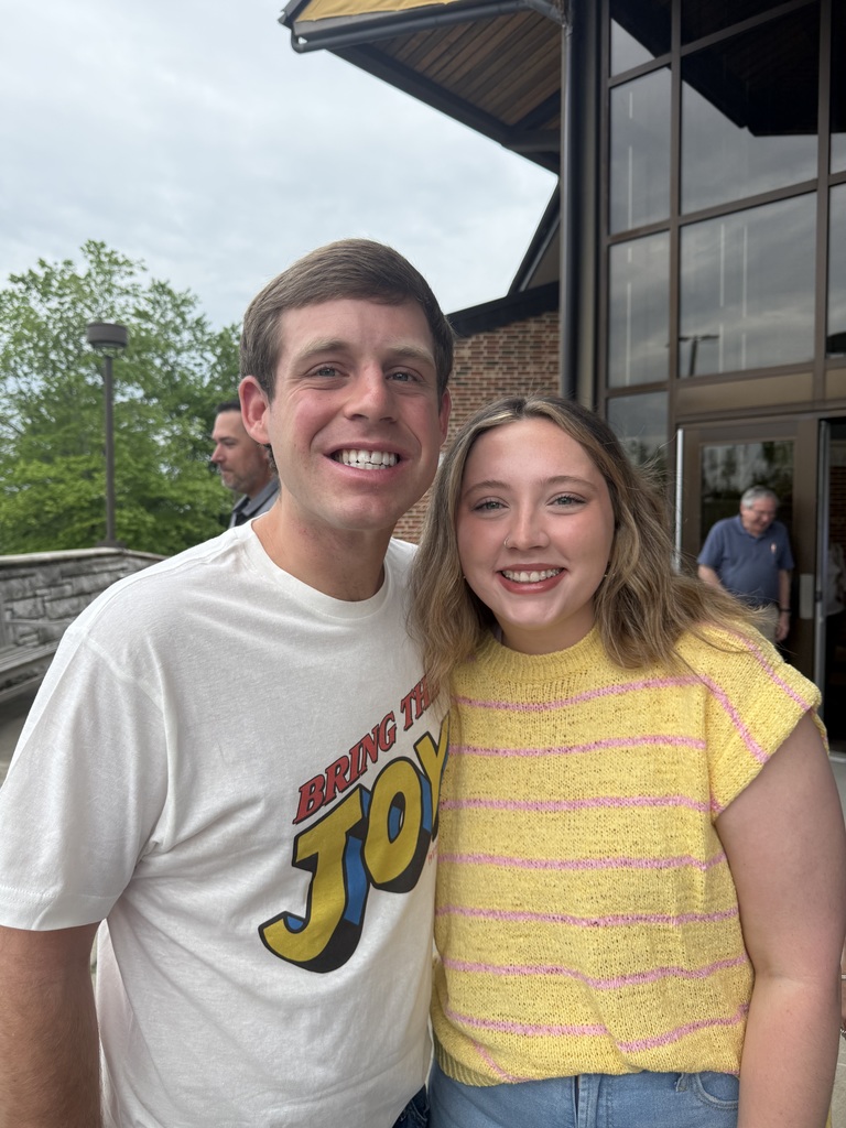 woman and a man standing outside close together with their arms around each other. 