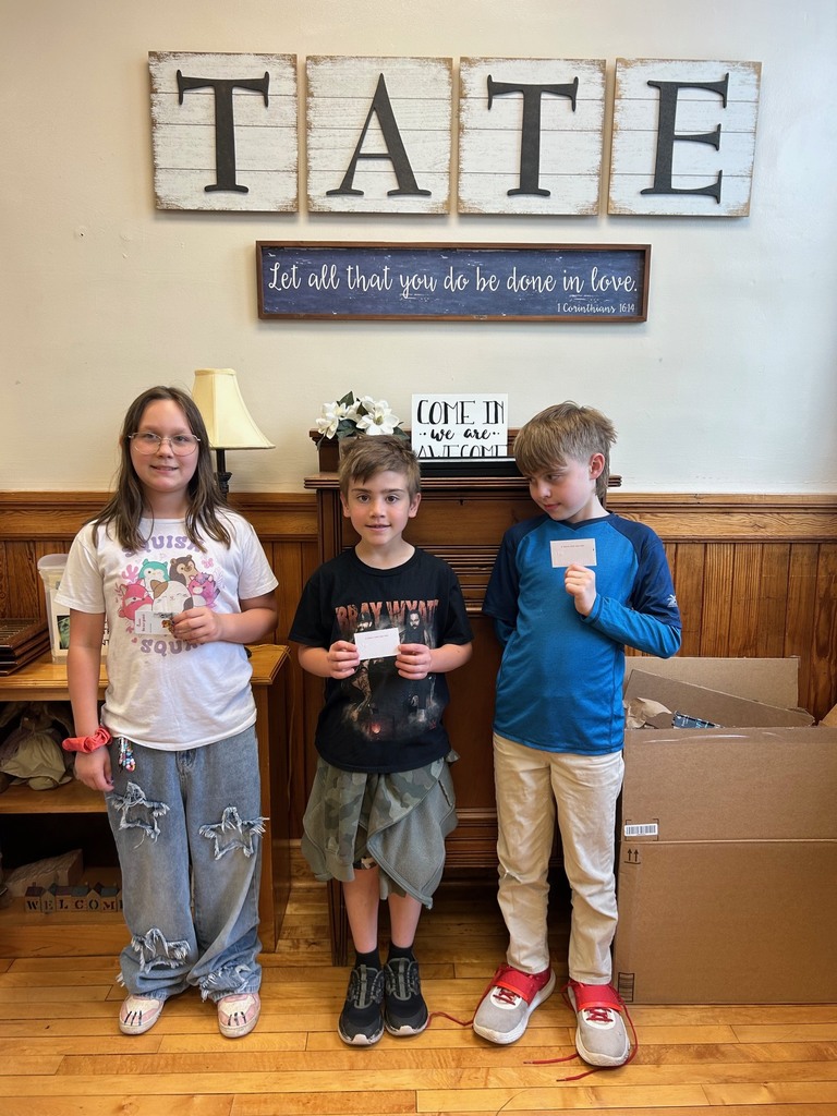 Three kids standing in front a sign that says Tate. They are holding chick fil a giftcards