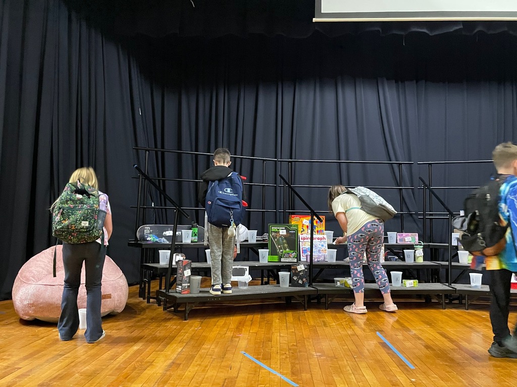 Four kids standing on a stage in front of a riser with prizes