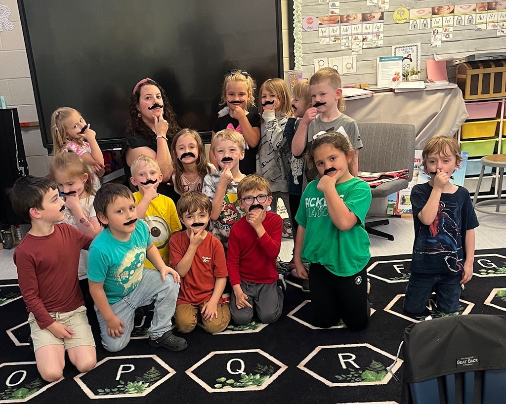 Group of kids and a teacher wearing fake Mustache's