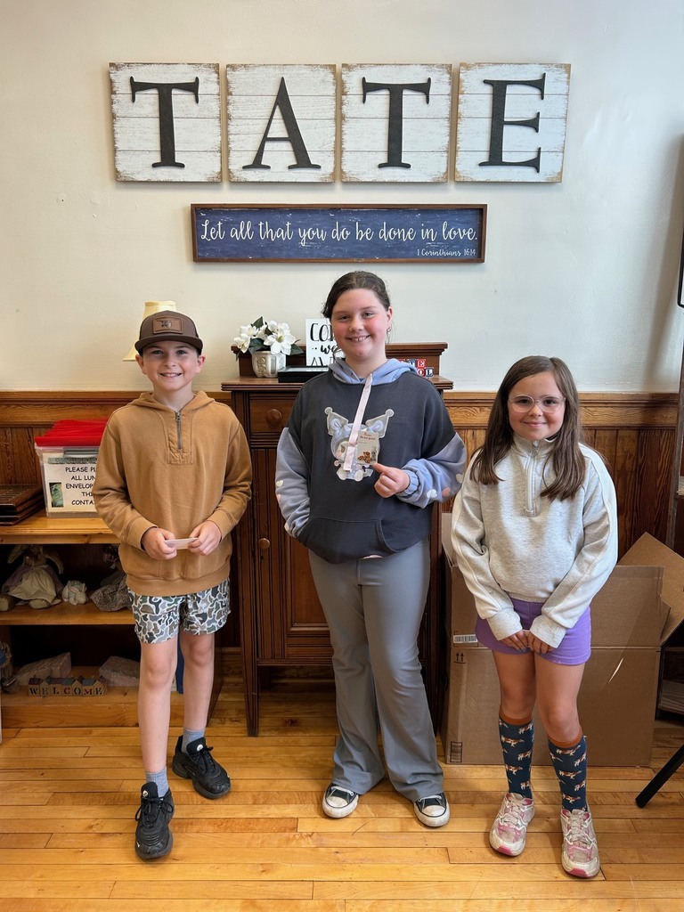Three kids standing in front a sign that reads TATE holdin chick fil a gift cards