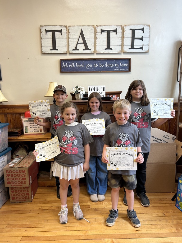 Five kids standing together in front of a sigh that reads TATE. All of them are wearing the same shirt and holding certificates.