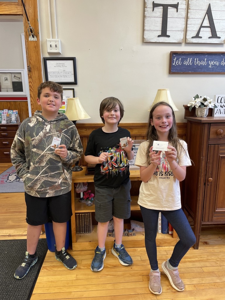 Three kids standing in a school office holding chick fil a gift cards