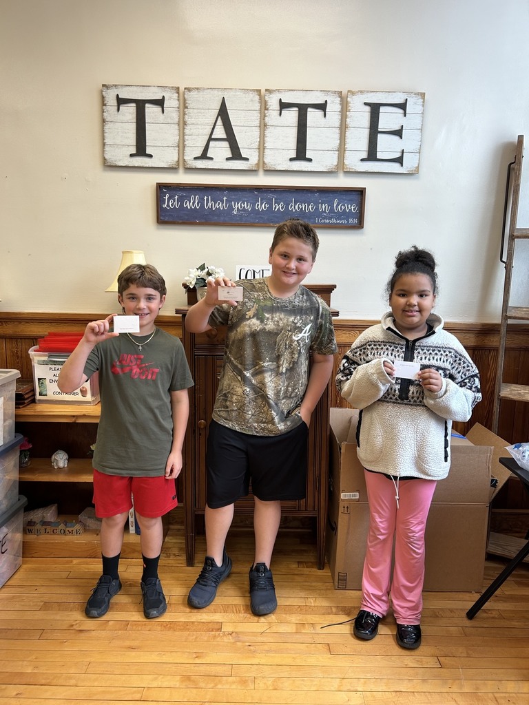 Three students standing in the office holding chick fil a gift cards