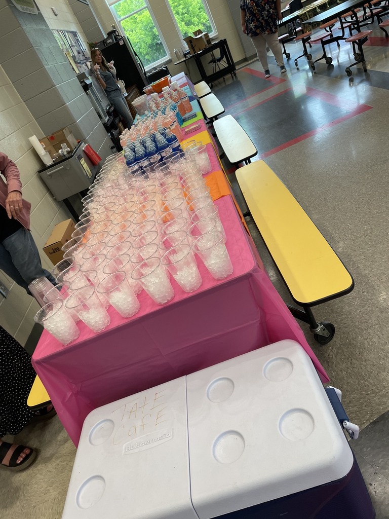Table with colorful tablecloths. Clear plastic cups filled with ice , and bottled waters are sitting on the tables. 