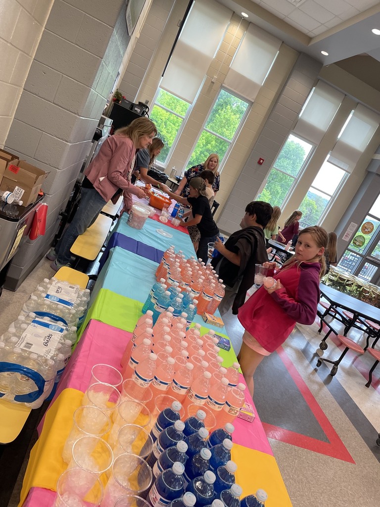 Table with colorful tablecloths. Clear plastic cups filled with ice , and bottled waters are sitting on the tables. 