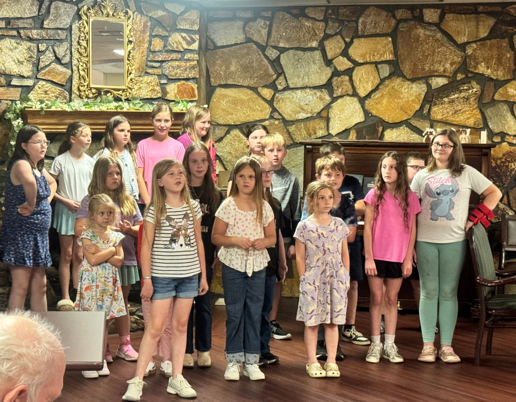 a group of children standing together in front of a rock wall