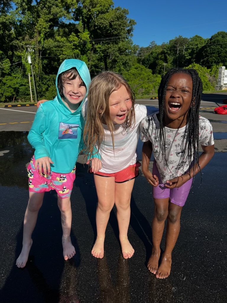 Three kids who are wet with water. They are all laughing.