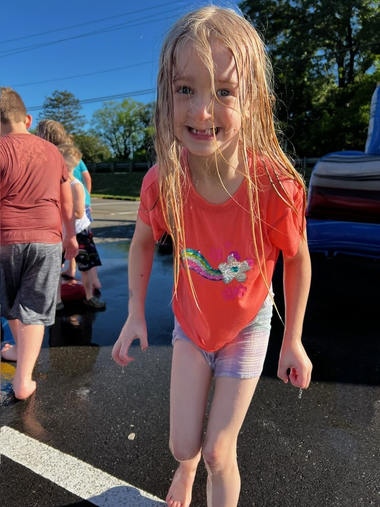 One small child standing. She is wet and smiling