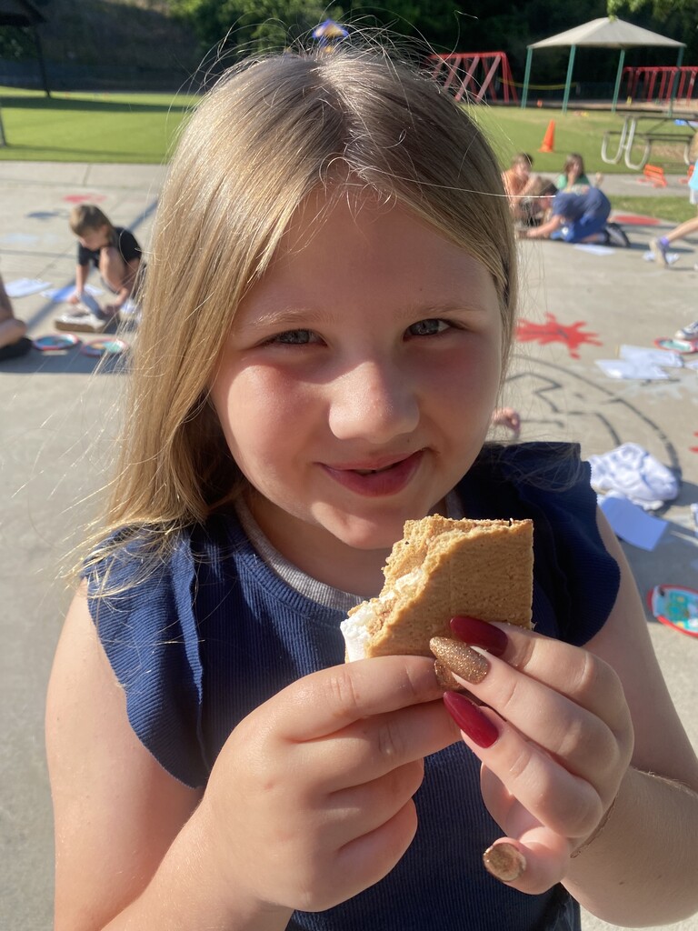 One female student holding a smores with a bite taken out of it.