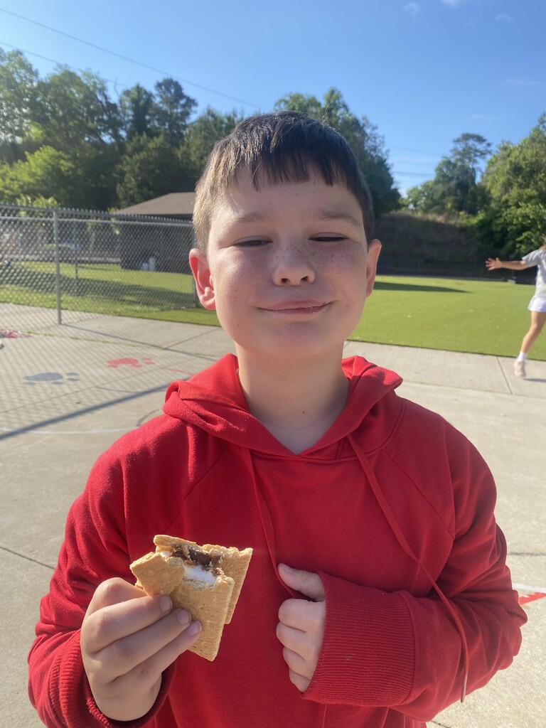 One male student holding a smores with a bite taken out of it.