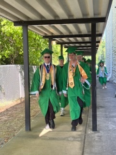 Two male high school students wearing green graduation gowns 