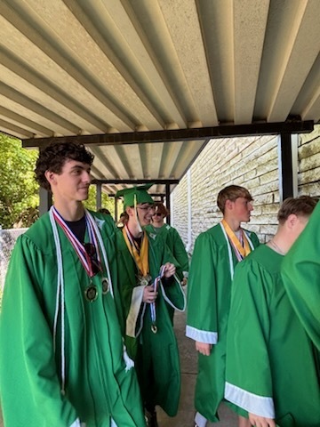 A group of male high school students wearing green graduation gowns 