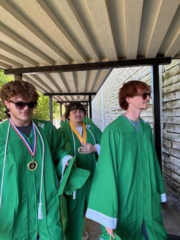 Three male high school students wearing green gradation gowns 