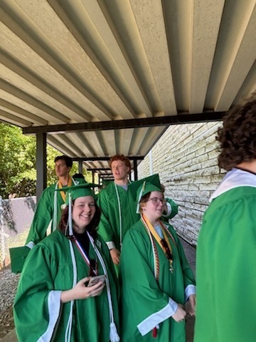 A group of high school students wearing green graduation gowns 