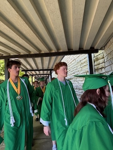 A group of high school students wearing green graduation gowns 