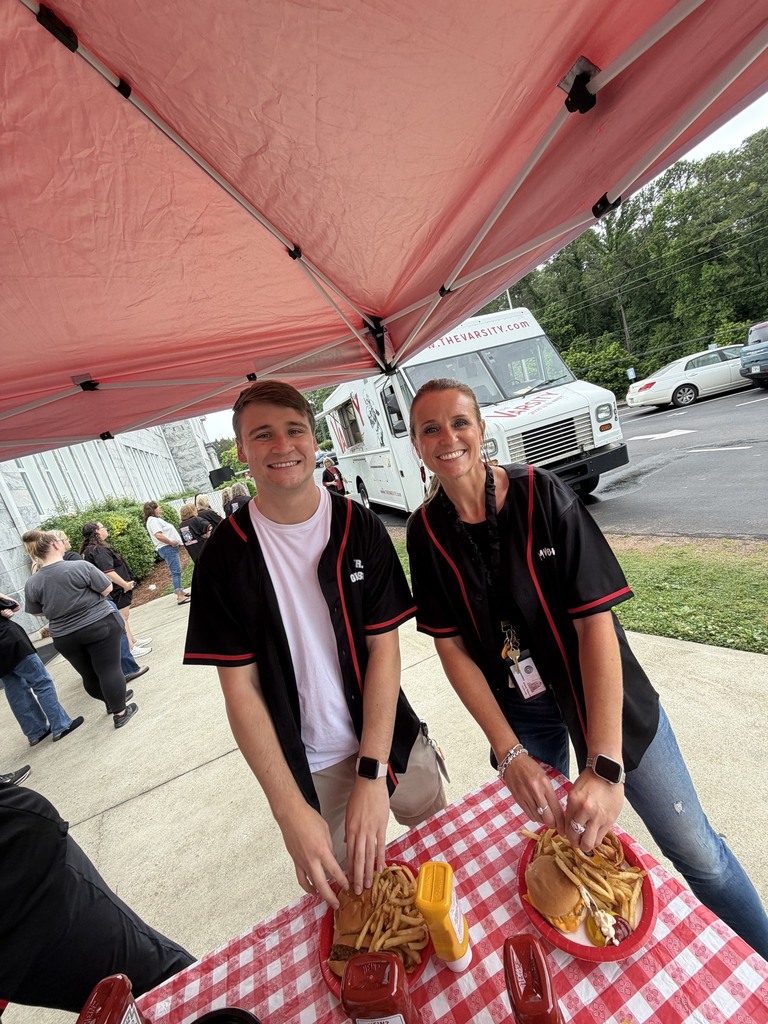 Two people standing at a table with food in front of them