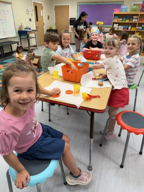 Classroom full of kids sitting at a table playing with playdough