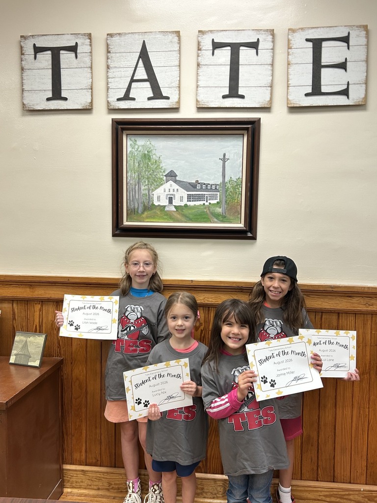 Four kids standing together, holding certificates, wearing matching shirts.