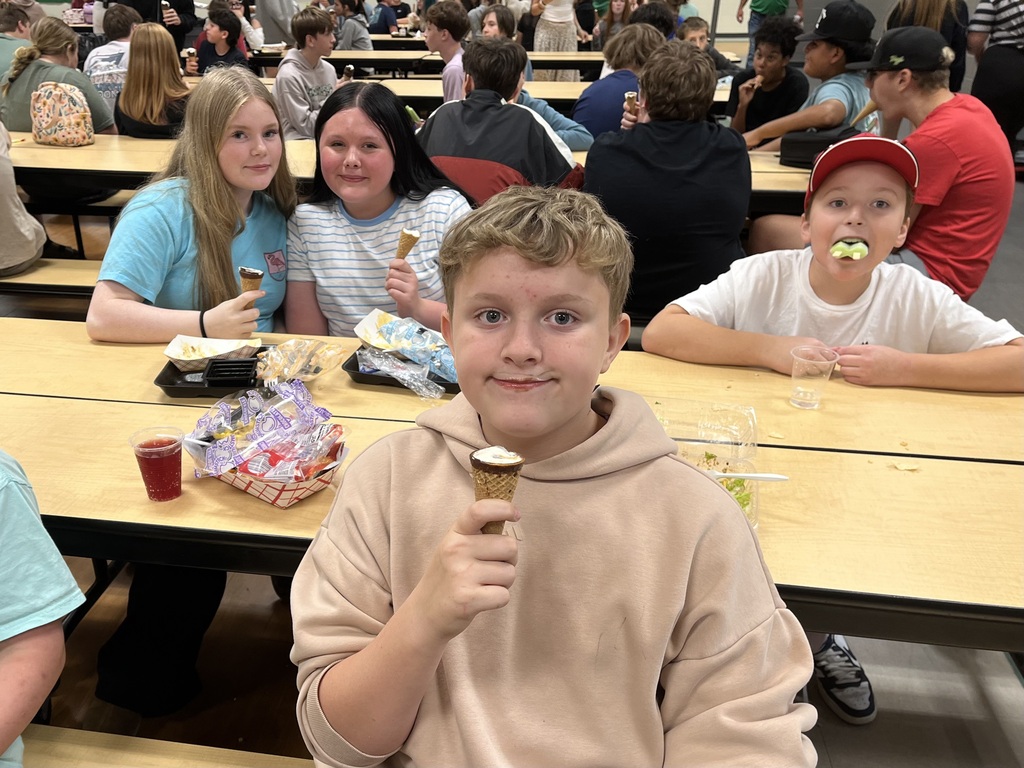Boy with ice cream mustache and three other eating ice cream behind him